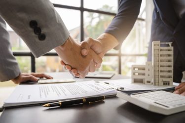 Close up shake hands, Considering buying a home, investing in real estate. Broker signs a sales agreement. agent, lease agreement, successful deal.
